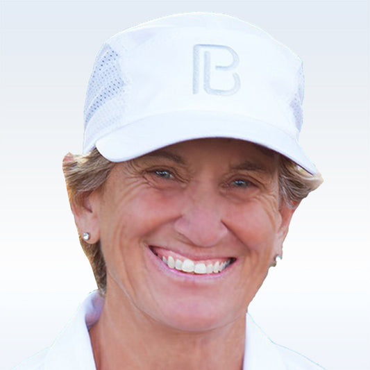 Woman wearing a white breathable visor hat with the letter "B" on the front smiles brightly.