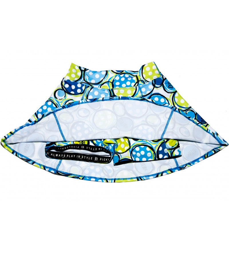 Blue and green polka-dot athletic skirt lays inside out, showcasing built-in shorts and motivational quote on the waistband.