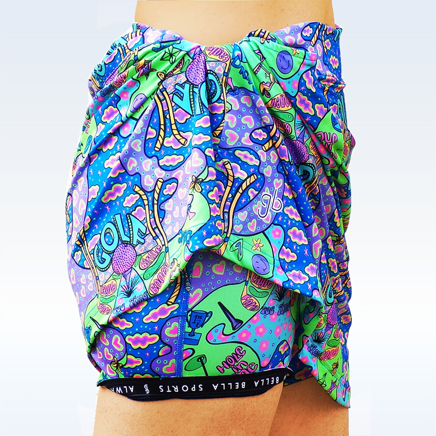 Woman models golf shorts with a colorful, psychedelic print featuring golf-themed doodles and phrases.