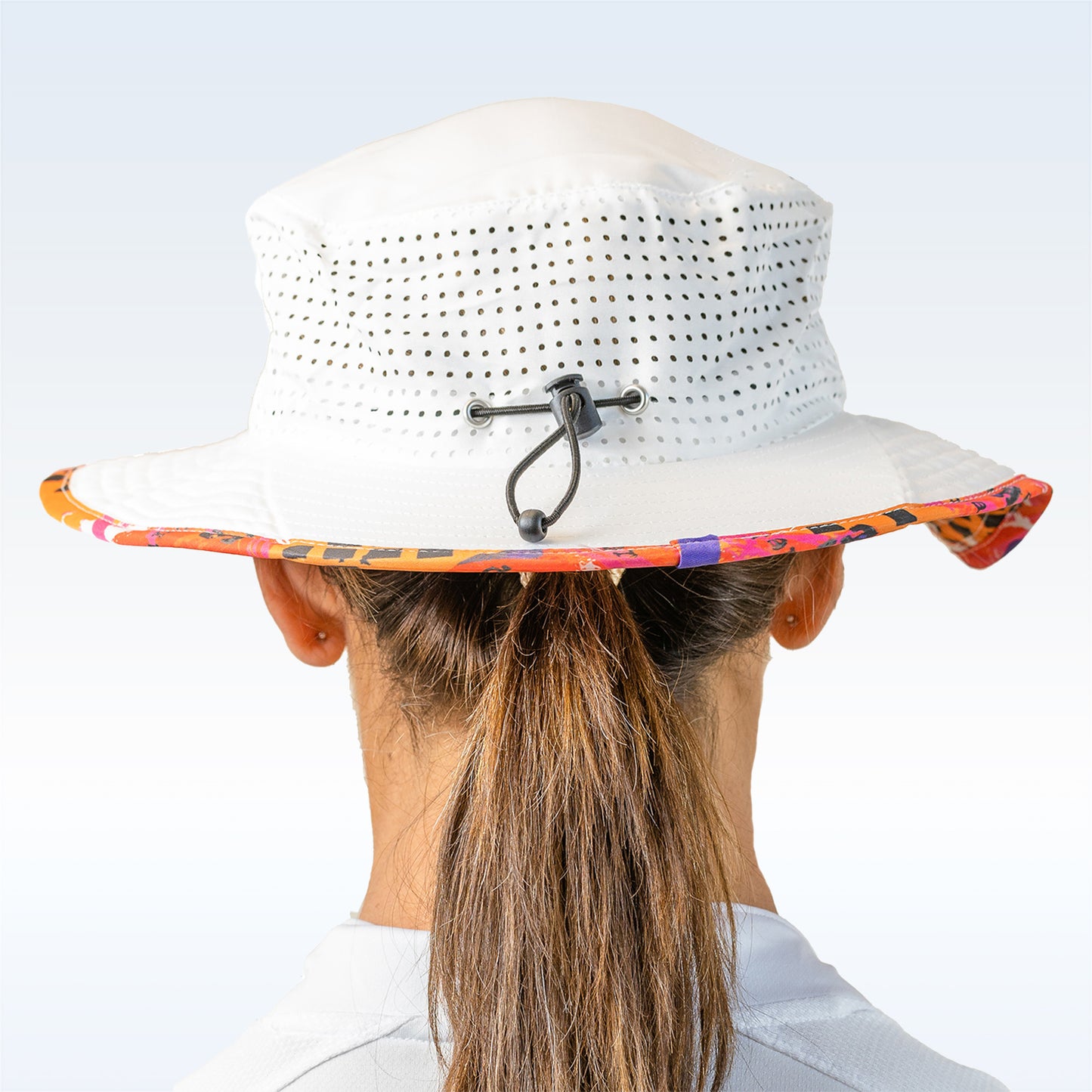 Woman models white bucket hat with colorful floral underbrim and adjustable black drawstring.
