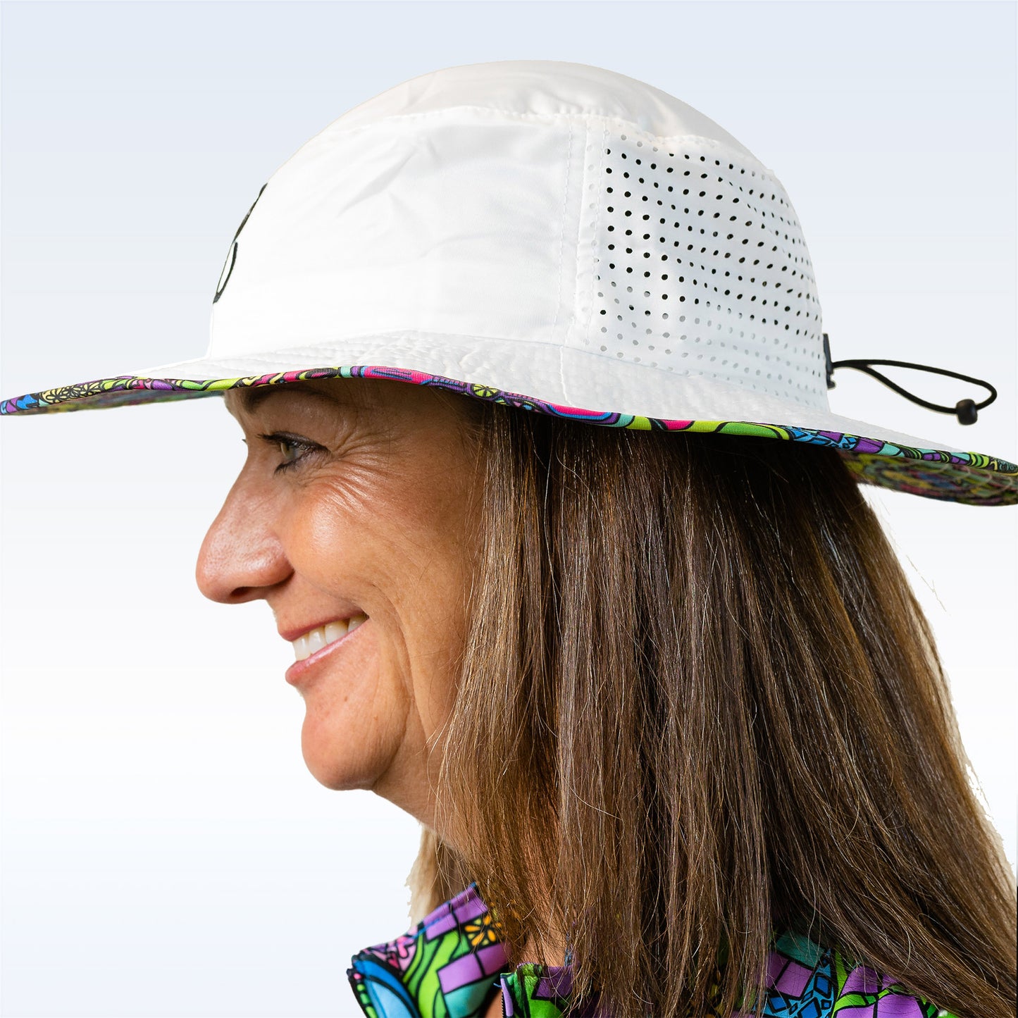 Woman smiles while wearing a white bucket hat with colorful floral trim and side ventilation.