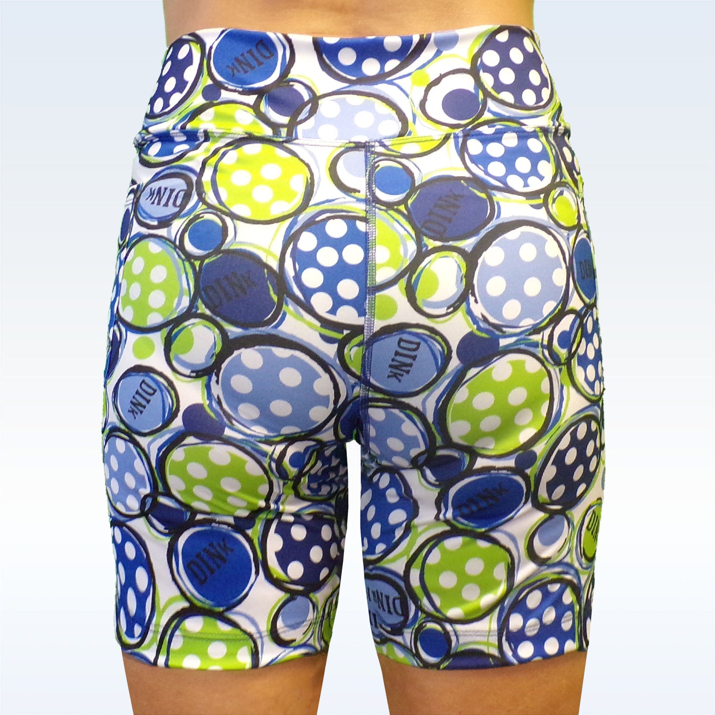 Woman models white athletic shorts with a blue, green, and white polka dot pattern.