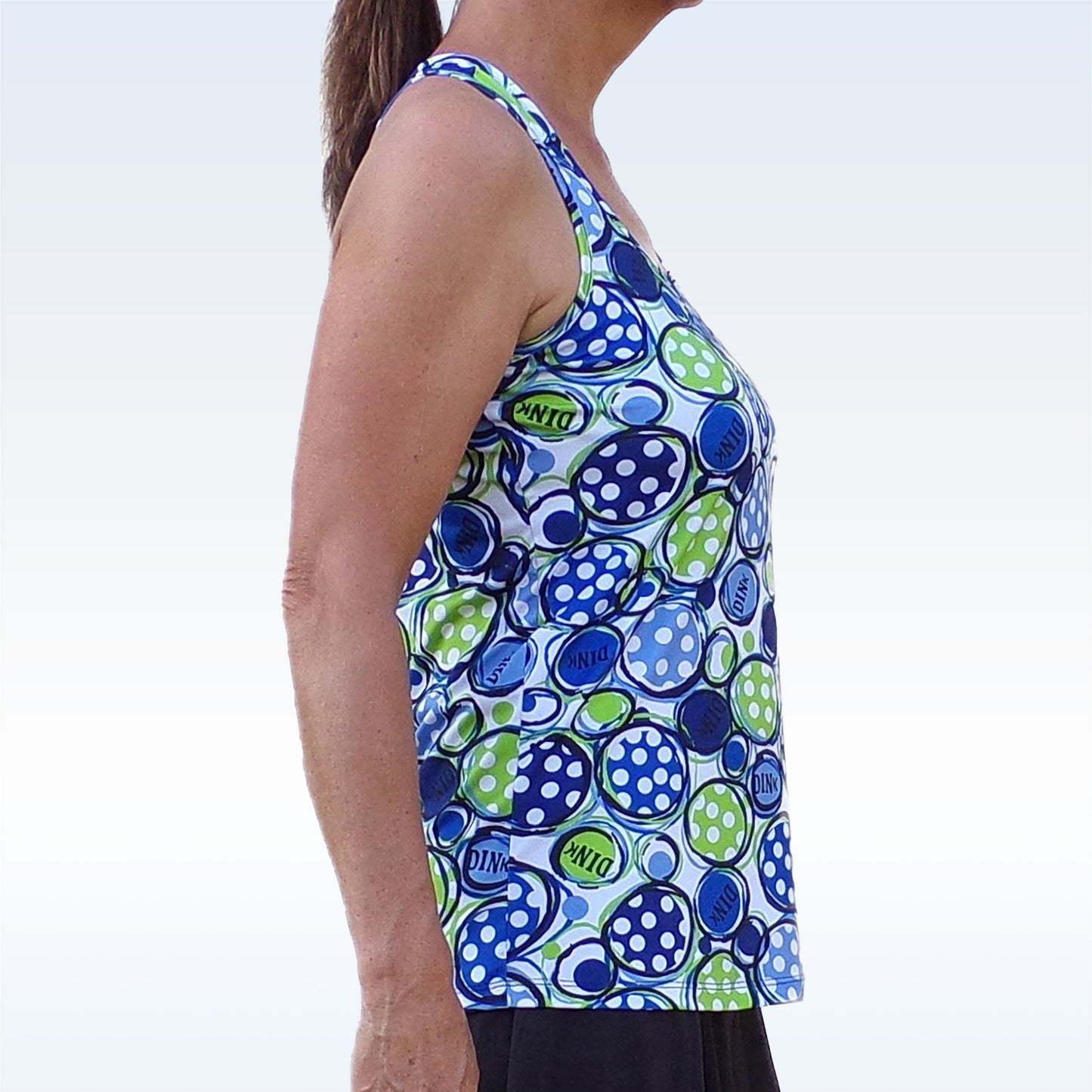 Woman models a white athletic tank top with a blue and green abstract polka dot pattern.