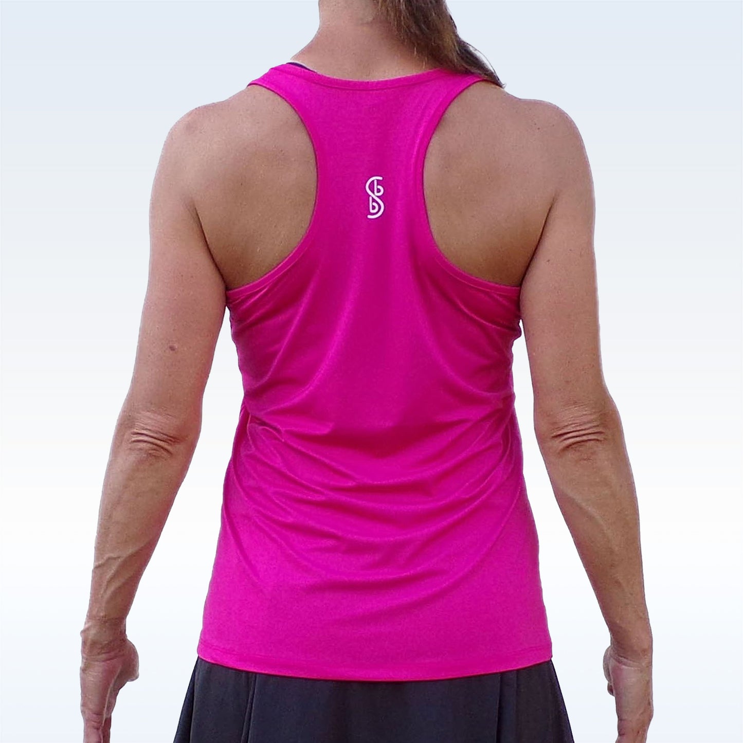 Woman models hot pink racerback tank top with white logo.