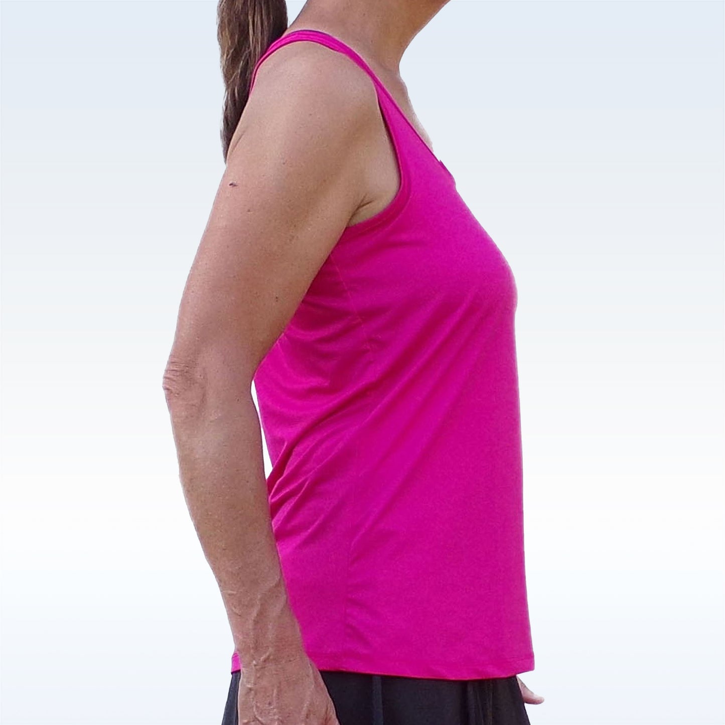 Woman models a hot pink athletic tank top with a black skirt.