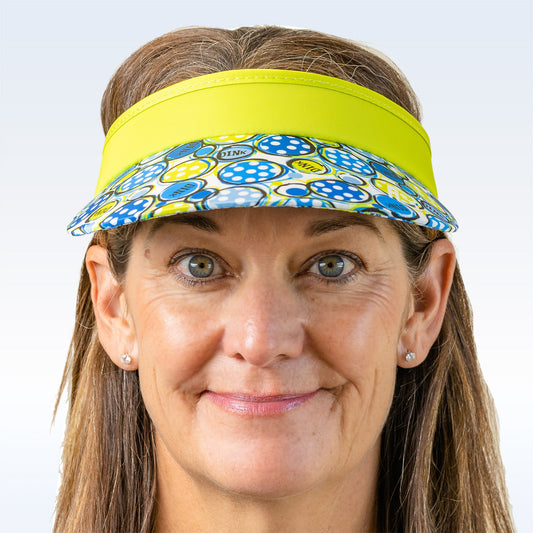 Woman smiles while wearing a blue and green patterned visor with a bright yellow brim.