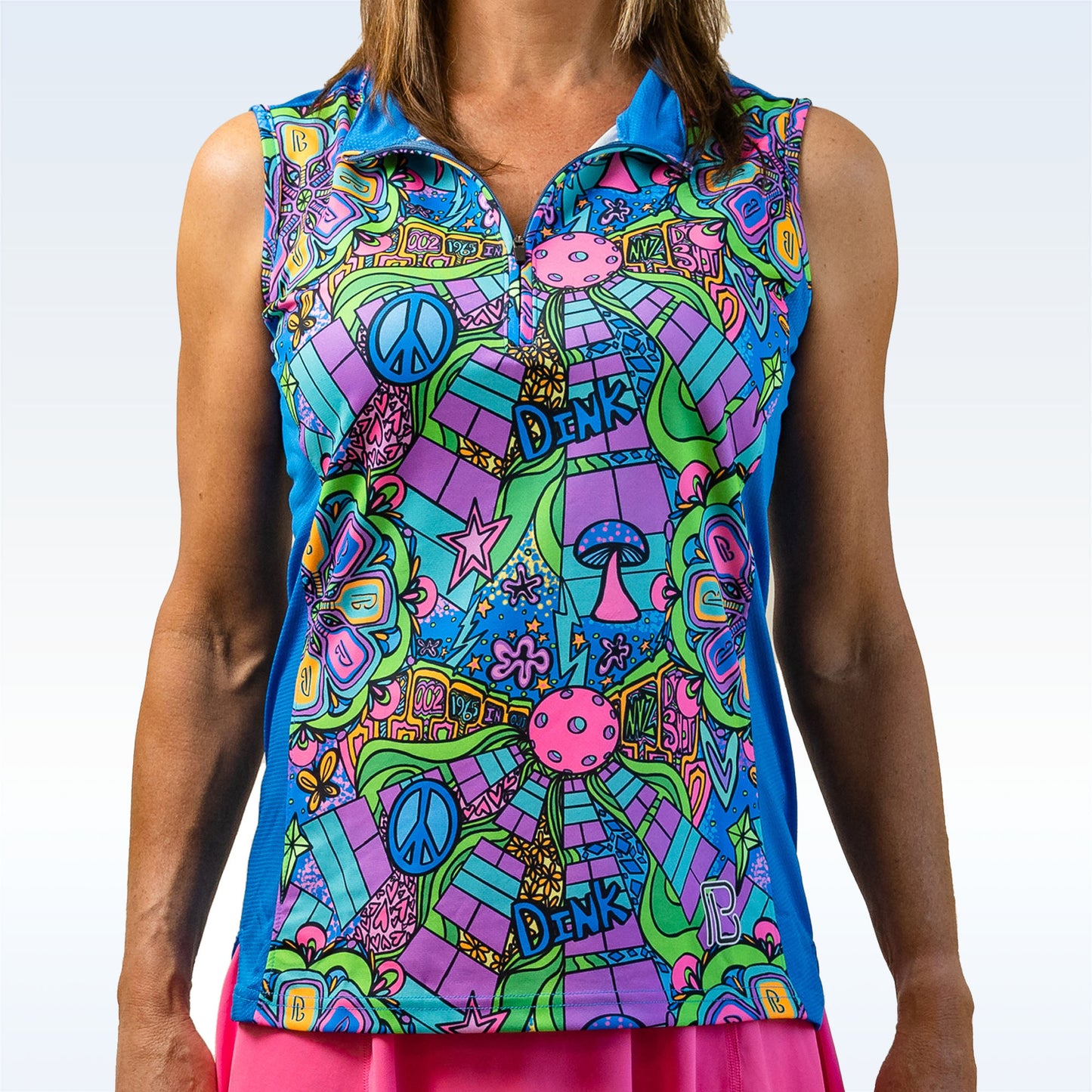 Woman models a sleeveless athletic top featuring a blue, green, and purple psychedelic print with pickleball and peace sign graphics. 
