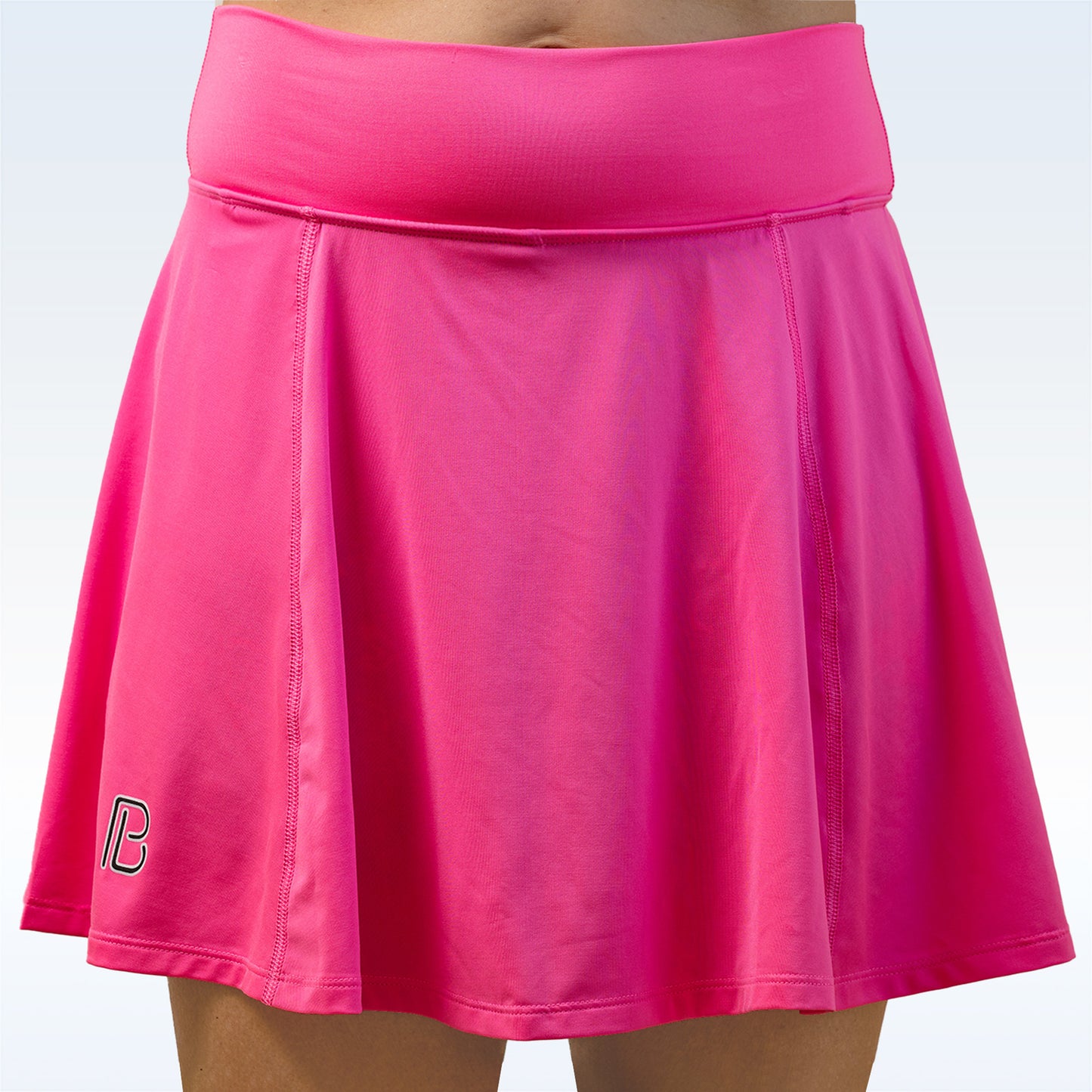 Woman models a bright pink athletic skirt with a comfortable waistband. 
