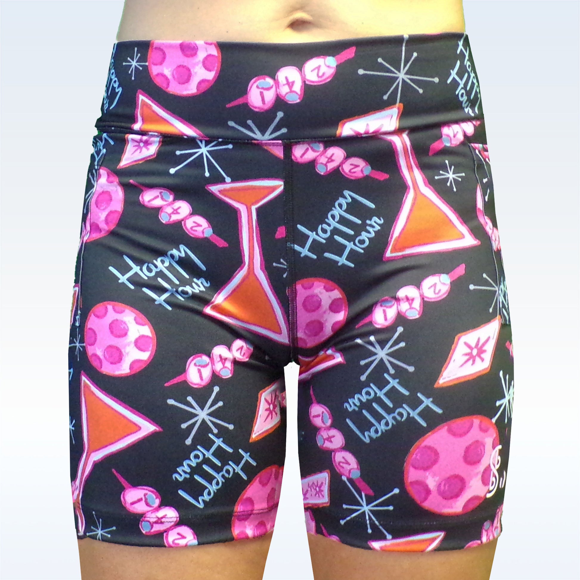 Woman models black athletic shorts featuring a pink, orange, and white "Happy Hour" cocktail print. 
